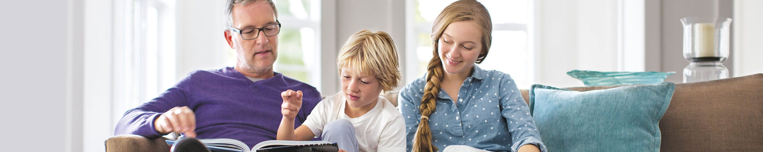 Ein Mann liest mit zwei Kindern ein Buch