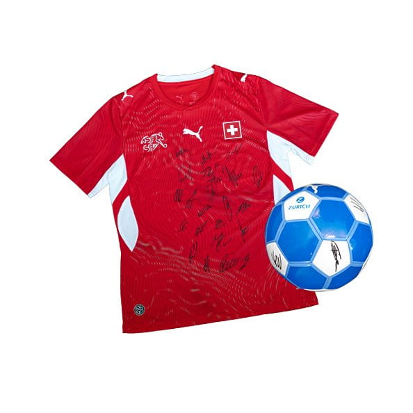 Un maillot de football rouge avec des autographes et un ballon de football bleu sont placés côte à côte.