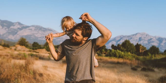 Un homme porte un enfant sur ses épaules dans un environnement naturel. Un homme porte un enfant sur ses épaules dans un environnement naturel.