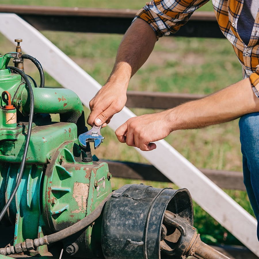 Ein Bauer repariert eine landwirtschaftliche Maschine.