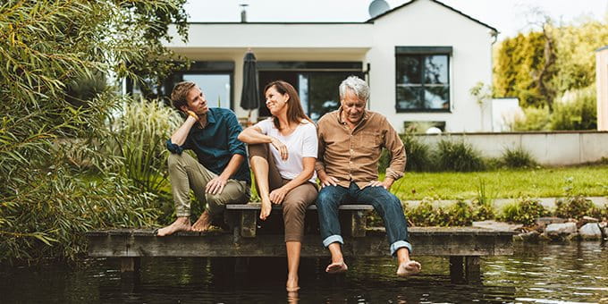 Tre persone sedute insieme su un pontile davanti a una casa sull’acqua. Tre persone sedute insieme su un pontile davanti a una casa sull’acqua.