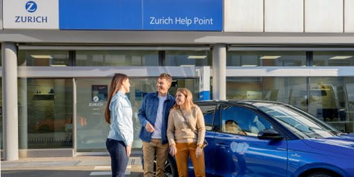 Drei Personen stehen vor einem blauen Auto und unterhalten sich vor einem Zürich Help Point.
